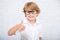 Close up portrait of cute little boy in glasses thumbs up