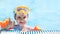 Close-up portrait of a cute little Caucasian girl swimming in the pool in a swimming mask and armbands, beach resort
