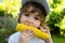 Close-up portrait of cute little child eating yellow sweet corncob corn.