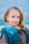 Close-up portrait of a cute little girl with a blond tress on the background of azure sea