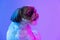 Close-up portrait of cute little Shih Tzu dog looking away isolated over purple neon background. Side view
