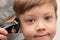 Close-up portrait of a cute preschooler boy whose female hands are cut with a hair clipper. look into the camera