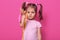 Close up portrait of cute, sad girl holds in hand skipping rope. Little child wants to play with somebody. Adorable kid with pony