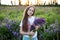 Close-up portrait of cute young girl  in a field of lupins. Girl holding a bouquet of purple flowers in background of a field of l