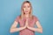 Close up portrait of cute young woman begging say please and show pleading gesture standing over blue background