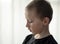 Close-up portrait of depressed young pre-school boy in black t-shirt looking down and thinking. Unhappy alone child with sad face