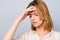 Close up portrait of dipressed young woman with short blonde hair having headache and touching her forehead