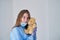 A close-up portrait of a doctor wearing an operating theatre outfit and brazing a teddy bear - isolated on a blue background.