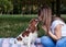 Close-up portrait of dog owner kissing small Cavalier king charles spaniel in park in summer. Young blond woman, having fun with