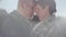Close up portrait of an embracing adult married couple standing in the cool windy sunny weather on the background of