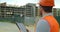 Close-up portrait of engineer with gadget on background of building under construction. Modern construction engineer or