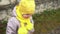 close-up Portrait of European little toddler dirty poor child grl in yellow knitted hat gray jacket smiling look at