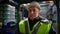 Close-up portrait of experienced Caucasian male forklift driver in hard hat sitting in vehicle looking around at stock