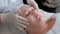 Close-up portrait of a fat woman on a procedure for cleaning the skin in a beauty salon. The hands of the cosmetologist