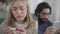 Close-up portrait of feared Caucasian woman looking at affirmative pregnancy test as her husband using tablet at the