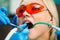 Close-up portrait of a female patient at dentist in the clinic. Teeth whitening procedure with ultraviolet light UV lamp.