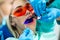 Close-up portrait of a female patient at dentist in the clinic. Teeth whitening procedure with ultraviolet light UV lamp