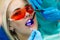 Close-up portrait of a female patient at dentist in the clinic. Teeth whitening procedure with ultraviolet light UV lamp