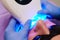 Close-up portrait of a female patient at dentist in the clinic. Teeth whitening procedure with ultraviolet light UV lamp