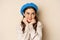 Close up portrait of feminine young woman in trendy french hat, posing cute and romantic, making silly coquettish face