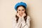 Close up portrait of feminine young woman in trendy french hat, posing cute and romantic, making silly coquettish face