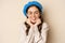 Close up portrait of feminine young woman in trendy french hat, posing cute and romantic, making silly coquettish face