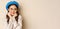 Close up portrait of feminine young woman in trendy french hat, posing cute and romantic, making silly coquettish face