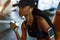 Close-up portrait of fitness instructor african american woman working out with dumbbells at the gym and listens music