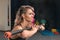 Close-up portrait of fitness woman with blond and pink long hair doing squats exercise with gymnastic stick. Blurred background of