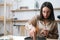 Close-up portrait of focused female artisan preparing glass vessel to pour mixture of liquid wax to create handmade