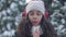 Close-up portrait of freezed African American teen girl blowing on hands standing outdoors on cold winter day. Charming