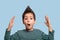 Close up  portrait of  a funny boy  surprising or delighting with something, raising his hands up on blue background in studio