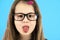 Close up portrait of a funny child school girl wearing looking glasses isolated on blue background