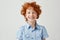 Close up portrait of funny little boy with orange hair and freckles mowing eyes, smiling and making silly faces for