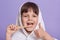 Close up portrait of funny pleasant happy little girl making gesture, showing sign super, thumb up, having towel on head, brushing