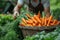 Close up portrait gardener with bunch of carrots in hand in garden