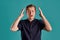 Close-up portrait of a ginger guy in navy t-shirt posing on blue background. Sincere emotions.