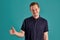 Close-up portrait of a ginger guy in navy t-shirt posing on blue background. Sincere emotions.