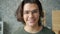 Close-up portrait of good-looking male student in glasses smiling in house