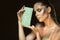 Close up portrait of gorgeous woman with closed eyes and artistic snakeskin make up holding green leather purse at her face