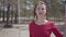 Close up portrait of graceful beautiful young woman in red dress sitting on the swing in the forest and looking an