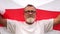 Close-up portrait of a gray-haired pensioner with glasses and a beard holding the red and white flag of Belarus. Protest