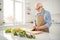 Close up portrait grey haired he his him grandpa hand arm knife cut down cucumber board making delicious cuisine