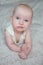 Close-up portrait of a grinning baby lying on the bed.