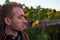 Close up portrait of a guy with shut eyes and sunflower.