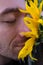 Close up portrait of a guy with shut eyes and sunflower.