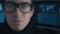 Close up Portrait Hacker programmer in glasses in dark cyber security center filled with display screens.