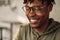 Close-up portrait of handsome African American man wearing glasses, smiling and looking down. positive, man`s look