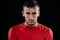 Close up portrait of handsome Caucasian sportsman wearing red sportswear and posing after exercises on dark background. Healthy in