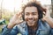 Close-up portrait of handsome unshaved dark-skinned guy holding hands on headphones while listening music and being